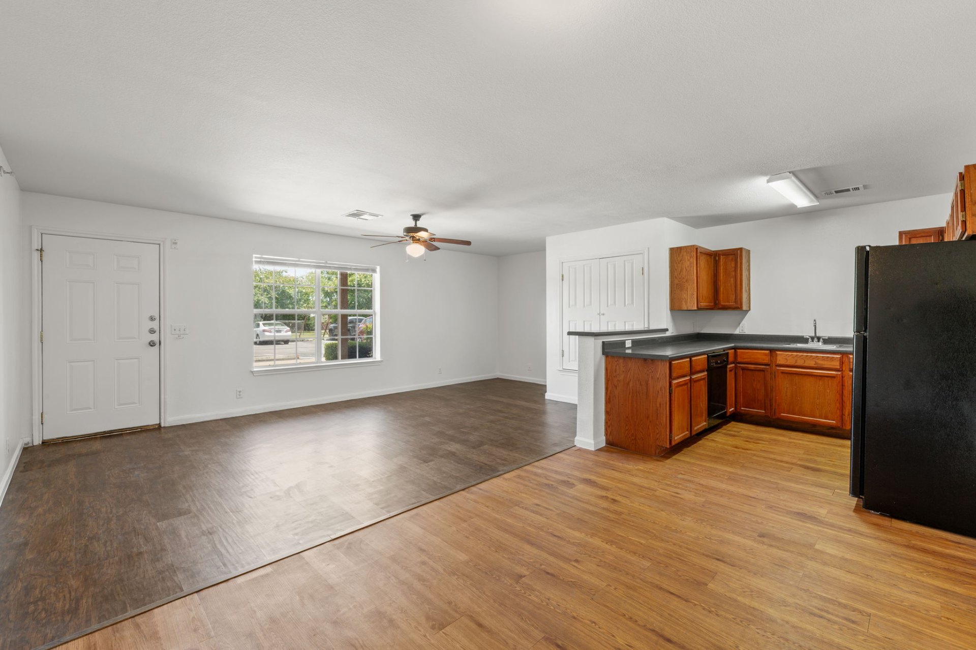 Classic-finish living room with large picture window and oak kitchen in back