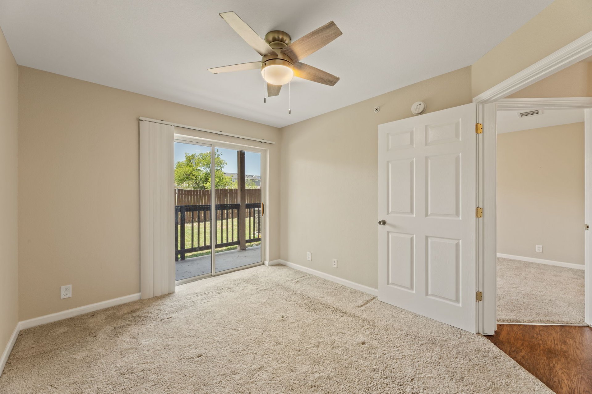 Carpeted bedroom with ceiling fan and private patio access