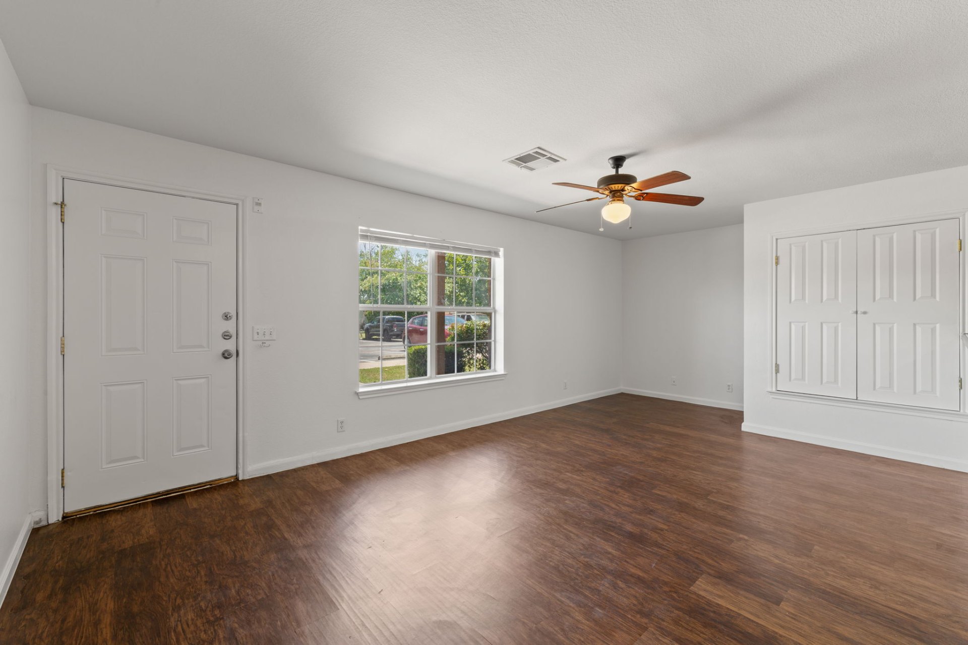 Bright living room with entry door, large picture window, and vinyl plank floors
