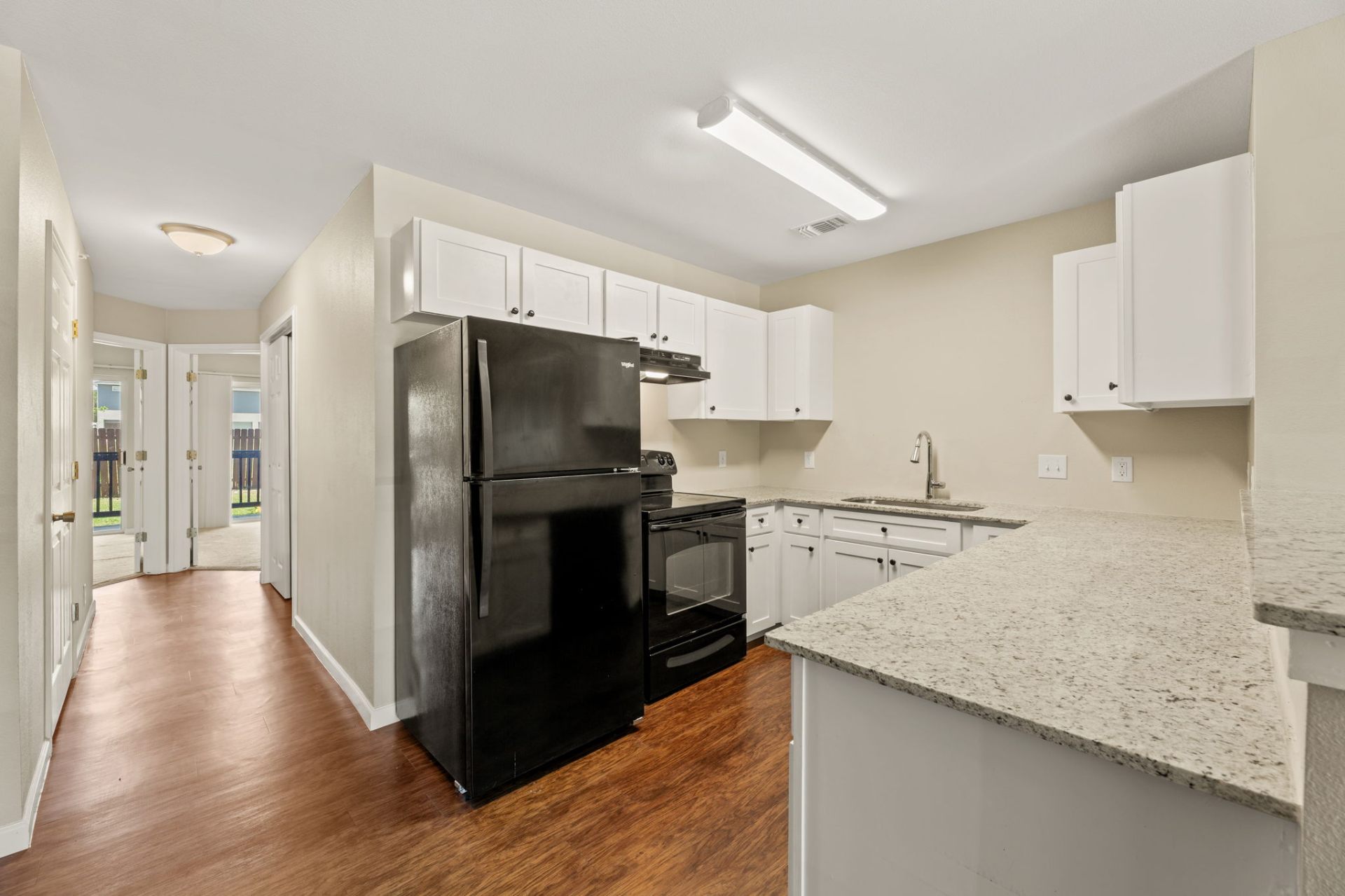 Kitchen with granite countertops, white shaker cabinets, and black appliances