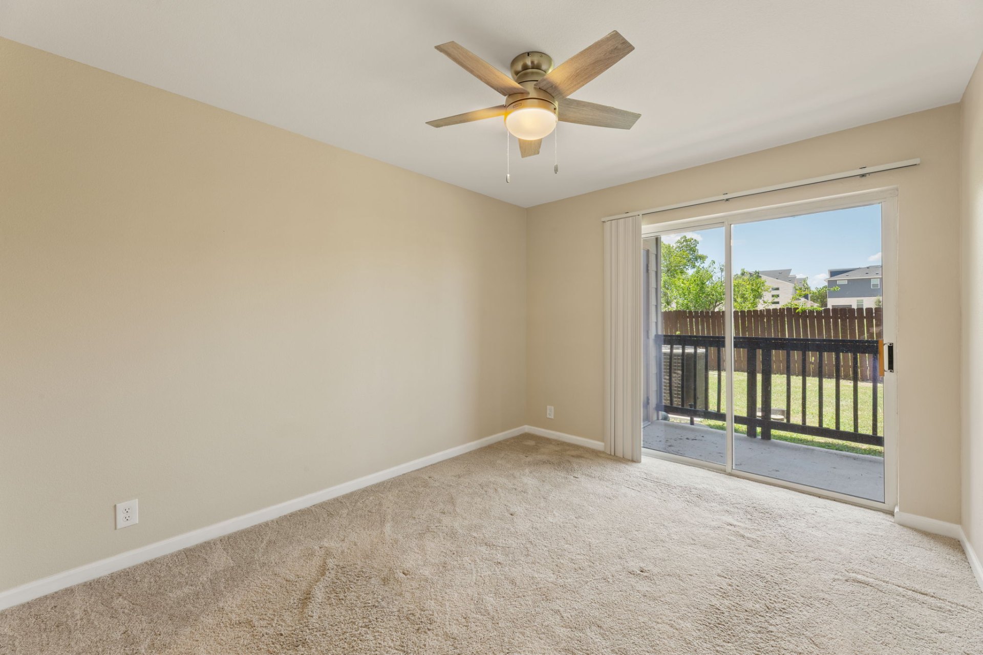 Carpeted bedroom with ceiling fan and sliding glass door to the yard